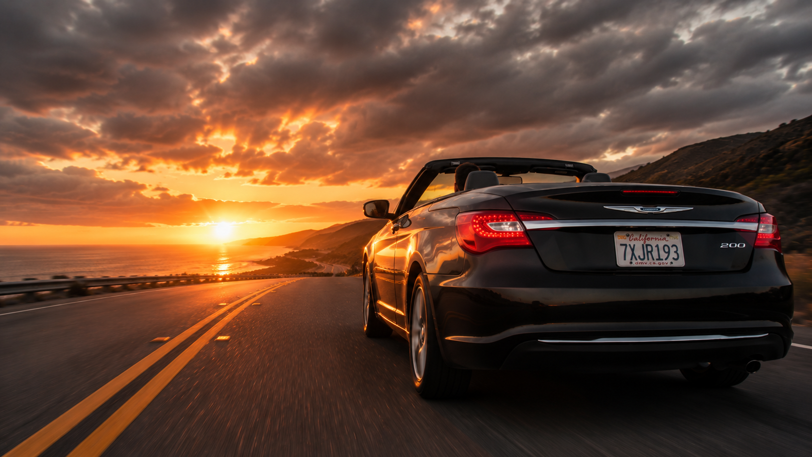 Black convertible driving toward the sunset on a coastal highway